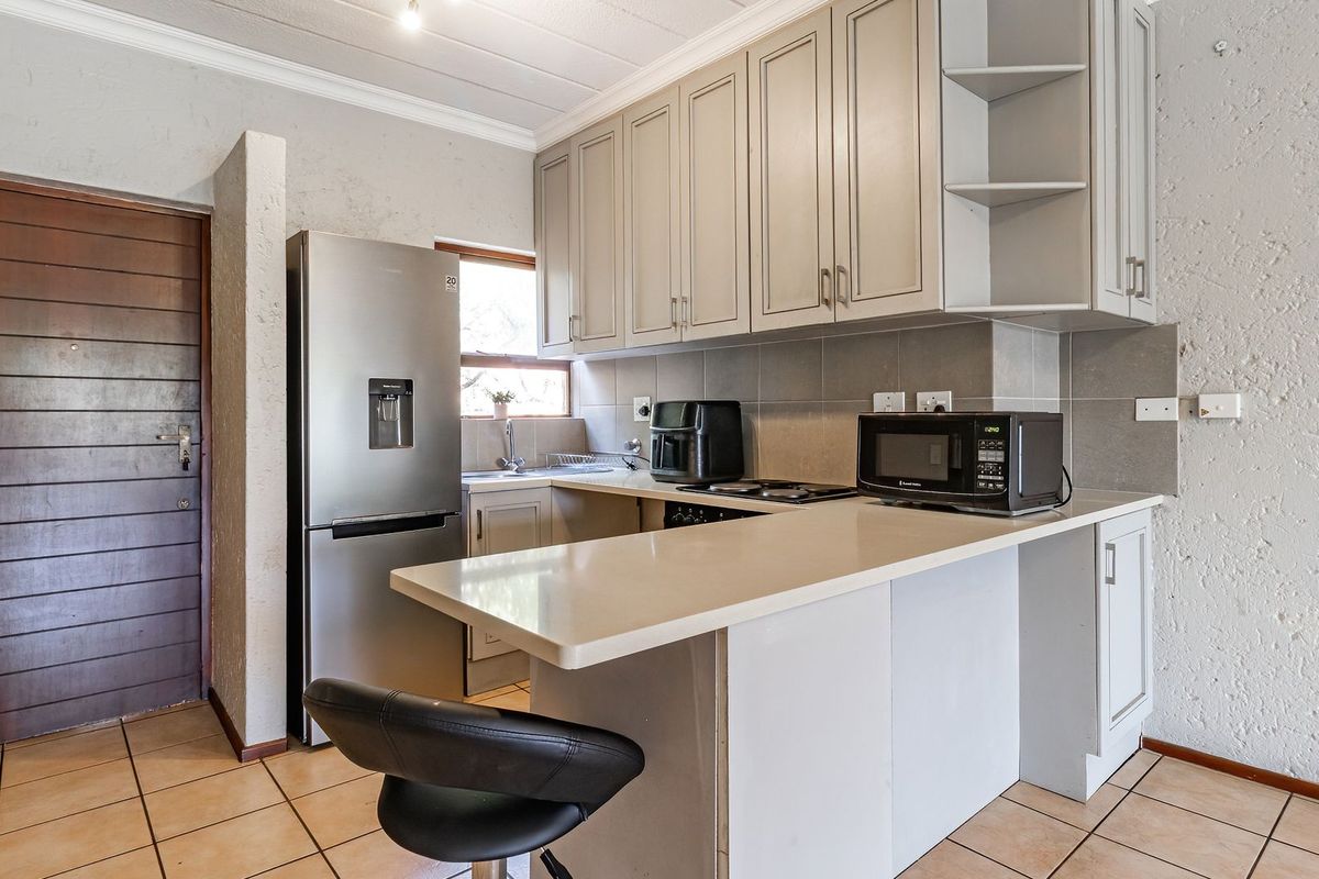 A functional kitchen featuring built-in cabinetry, stone countertops, a breakfast bar, and tiled flooring, offering a practical layout for daily use.