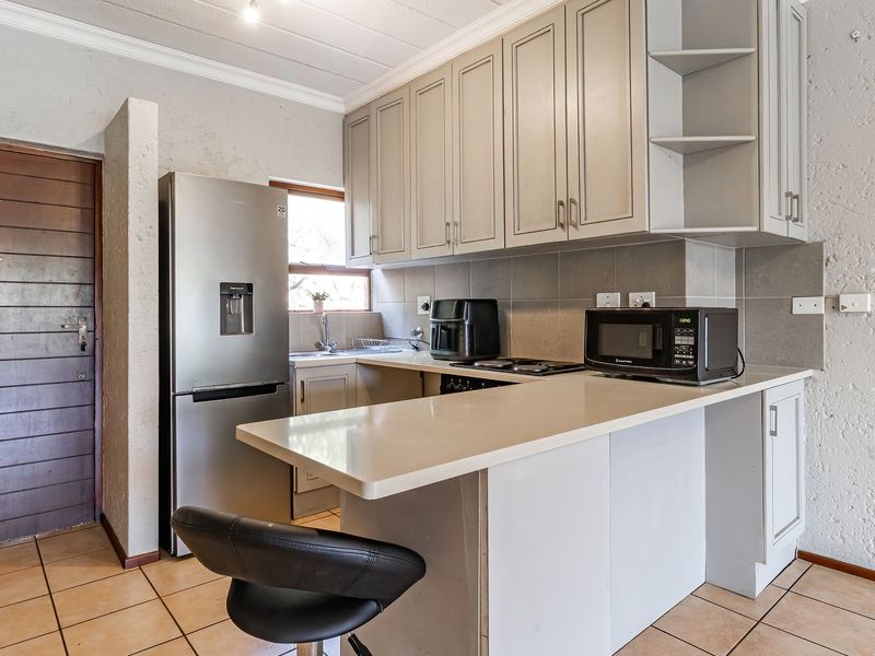 A functional kitchen featuring built-in cabinetry, stone countertops, a breakfast bar, and tiled flooring, offering a practical layout for daily use.