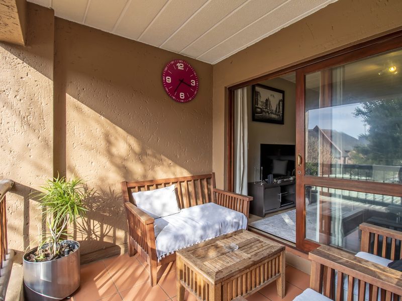 A covered balcony featuring tiled flooring, textured walls, and a large sliding glass door providing access to the interior living space.