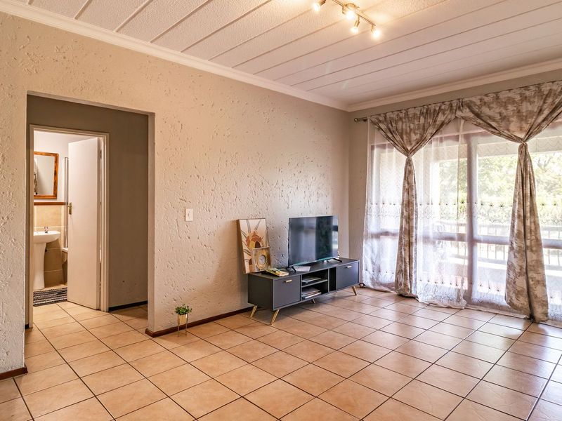 A living room featuring tiled flooring, textured walls, and a sliding glass door providing access to the exterior.