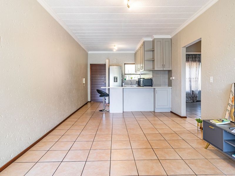 Open-plan living area featuring tiled flooring, textured walls, and a functional kitchen with built-in cabinetry and a central island.