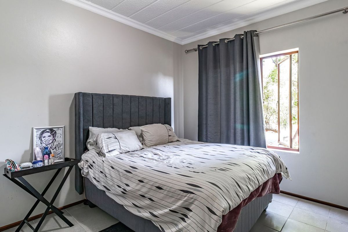 A functional bedroom featuring tiled flooring, a casement window with curtain rod, and coved ceiling detailing.