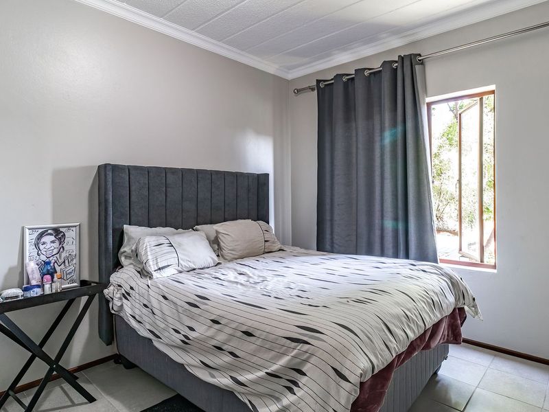A functional bedroom featuring tiled flooring, a casement window with curtain rod, and coved ceiling detailing.