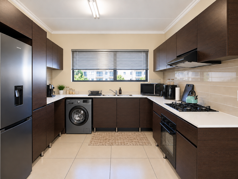 Modern kitchen featuring dark wood cabinetry, white stone countertops, integrated gas hob, built-in oven, and a double sink with tiled backsplash.