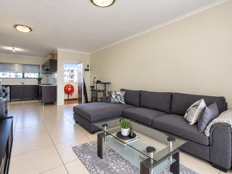 Open-plan living area featuring tiled floors, a modern kitchen with built-in cabinetry, and direct access to an outdoor balcony area.