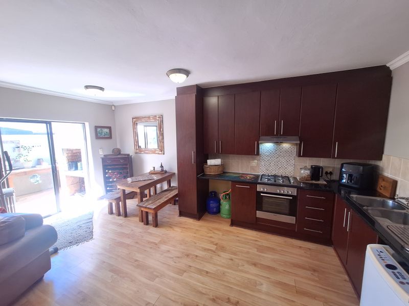 Open-plan kitchen and dining area featuring dark wood cabinetry, gas hob, built-in oven, and direct access to an outdoor patio through sliding glass doors.