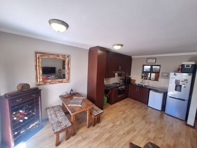 Open plan kitchen and dining area featuring dark wood cabinetry, laminate flooring, and functional built-in appliances.