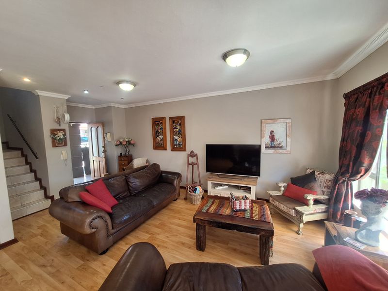 A comfortable living room featuring laminate flooring, a staircase, and coved cornicing, providing a functional and inviting space for relaxation.