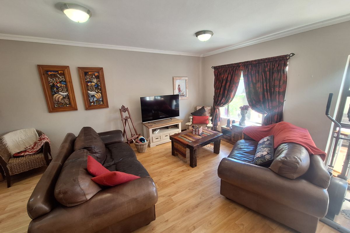 A comfortable living room featuring laminate flooring, neutral wall tones, and ceiling-mounted lighting, providing a functional and inviting space for relaxation.