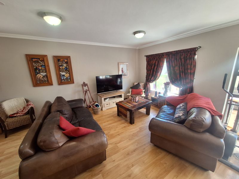 A comfortable living room featuring laminate flooring, neutral wall tones, and ceiling-mounted lighting, providing a functional and inviting space for relaxation.