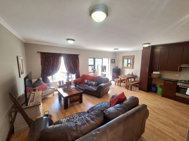 Spacious open-plan living area featuring laminate flooring, integrated kitchen cabinetry with built-in appliances, and direct access to the outdoor patio through sliding glass doors.