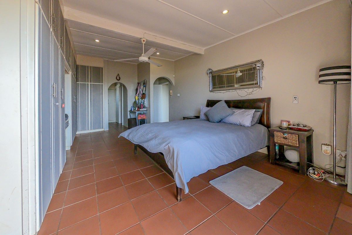 Spacious bedroom featuring built-in cupboards, tiled flooring, a ceiling fan, and recessed lighting, with an open archway leading to adjacent areas.