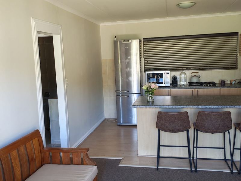 Open plan living and kitchen area featuring a breakfast bar, built-in cabinetry, and a mix of carpet and laminate flooring.
