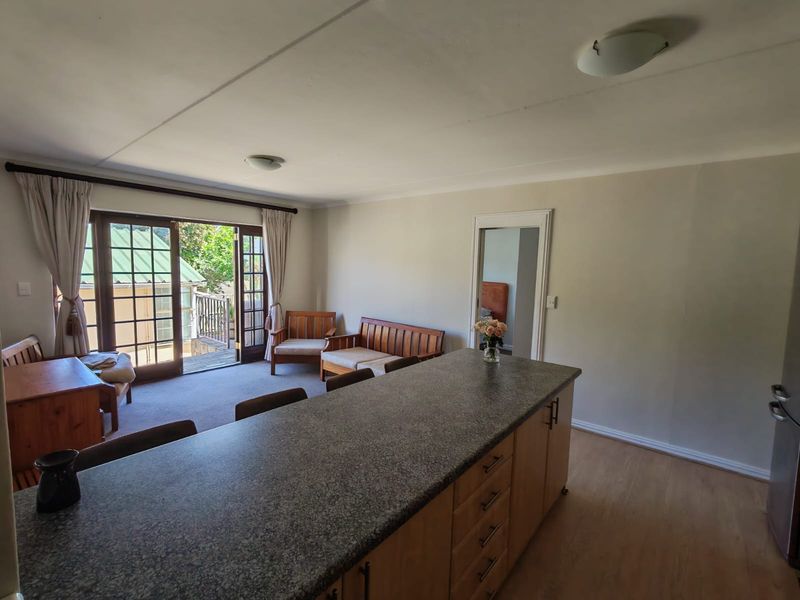 Open plan living area featuring a kitchen island with granite countertops and direct access to an outdoor patio through glass french doors.