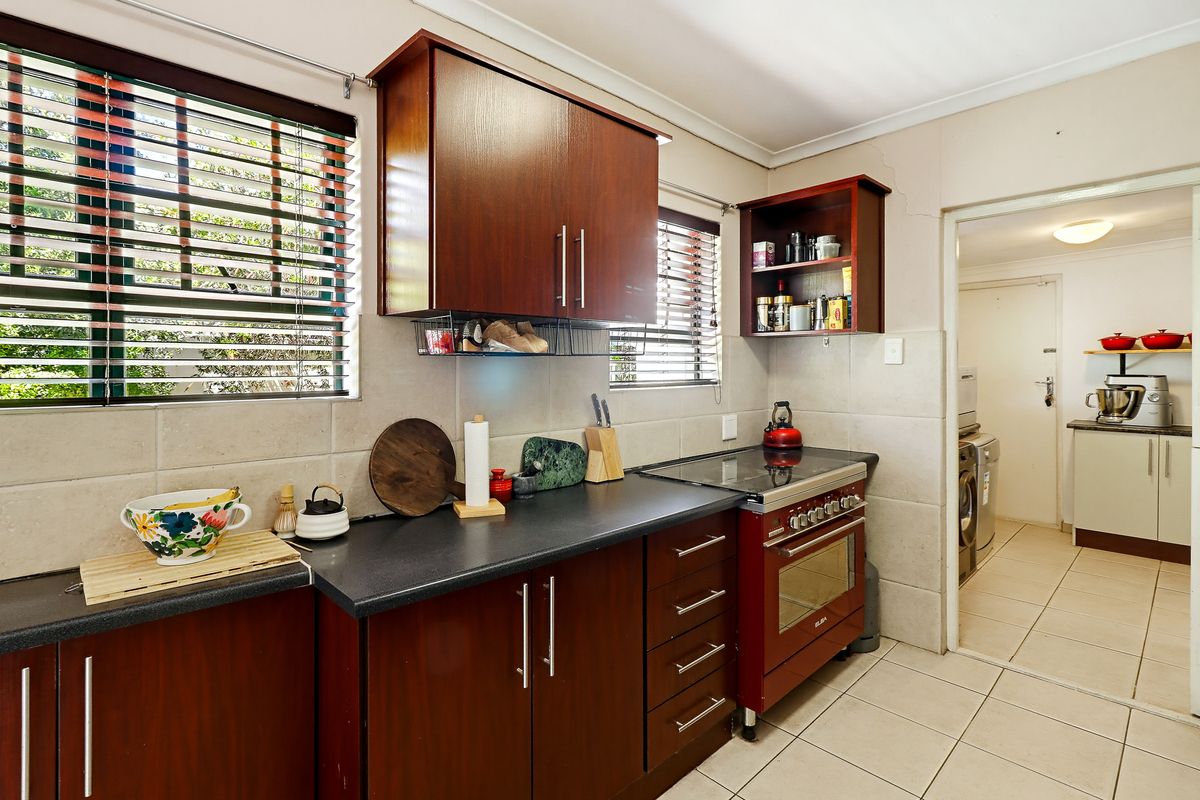 Functional kitchen featuring dark wood cabinetry, laminate countertops, and a freestanding oven, with an adjacent laundry area visible through the doorway.