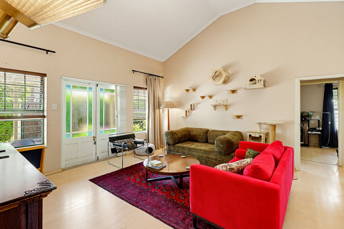 Spacious living room featuring a high vaulted ceiling, laminate flooring, and direct access to the outdoors through glass-paneled french doors.