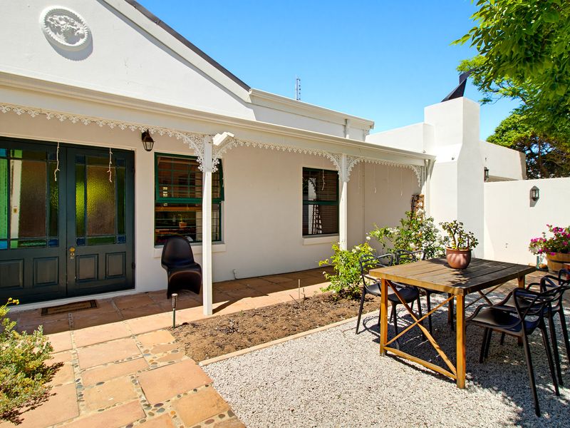 A charming covered patio area featuring terracotta tiling, decorative wrought iron fretwork, and a classic double door entrance with stained glass detailing.