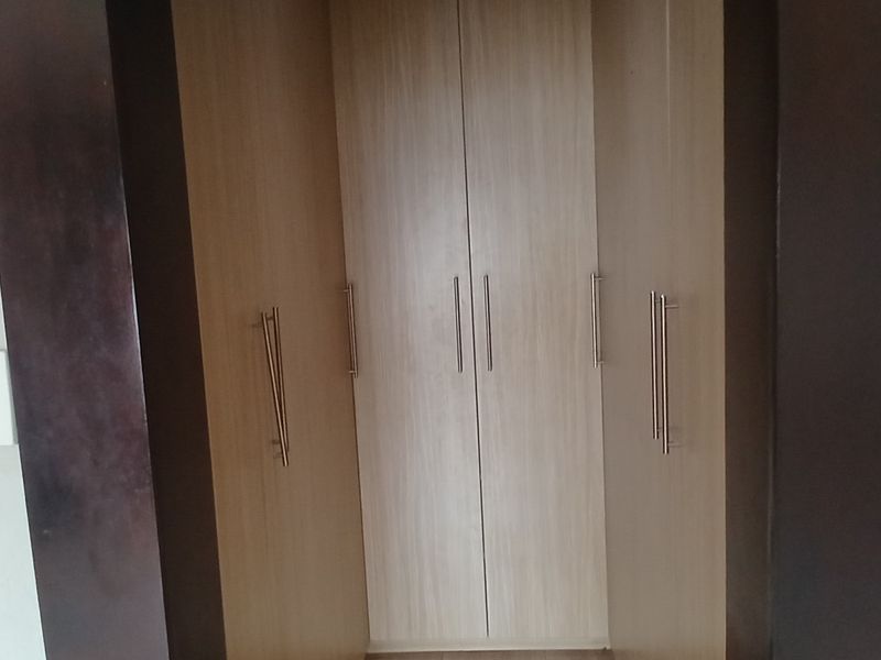 A view of built-in wooden cupboards with modern handles, integrated into a bedroom wall alcove.