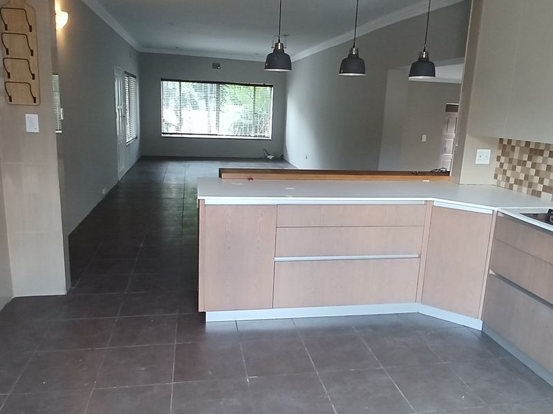 Spacious open-plan kitchen and living area featuring modern cabinetry, a gas hob, stone countertops, and neutral tiled flooring throughout.