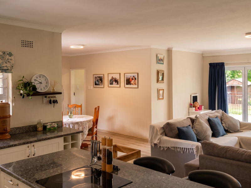 Spacious open-plan living area featuring a modern kitchen with granite countertops, flowing seamlessly into a bright lounge with direct access to the outdoor patio.