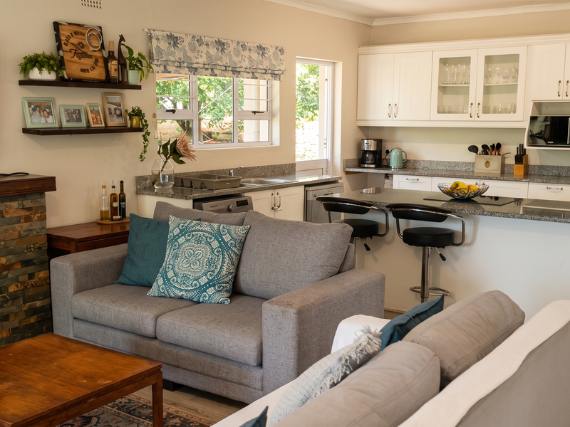 Open-plan living area featuring a stone-clad fireplace and a modern kitchen with granite countertops, island seating, and ample built-in cabinetry.