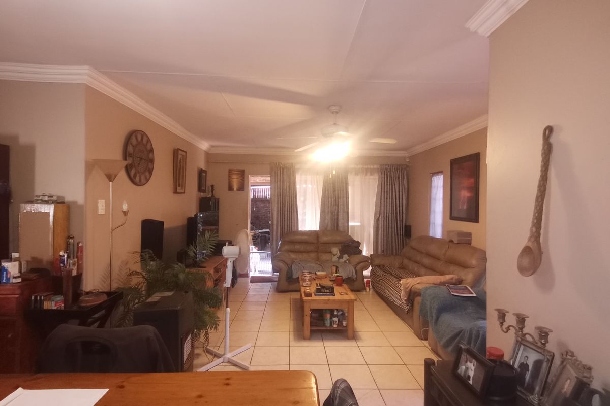 A spacious living room featuring tiled flooring, crown molding, and a ceiling fan, with direct access to the outdoor area through a sliding glass door.
