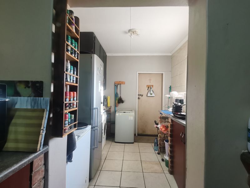 A functional laundry area featuring tiled flooring and brick-base cabinetry, providing essential utility space with direct access to the exterior.