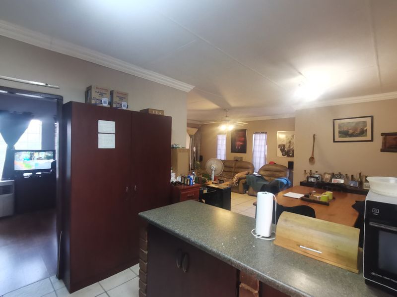 Open plan living and kitchen area featuring tiled flooring, coved ceilings, and a breakfast counter, offering a functional layout for daily living.