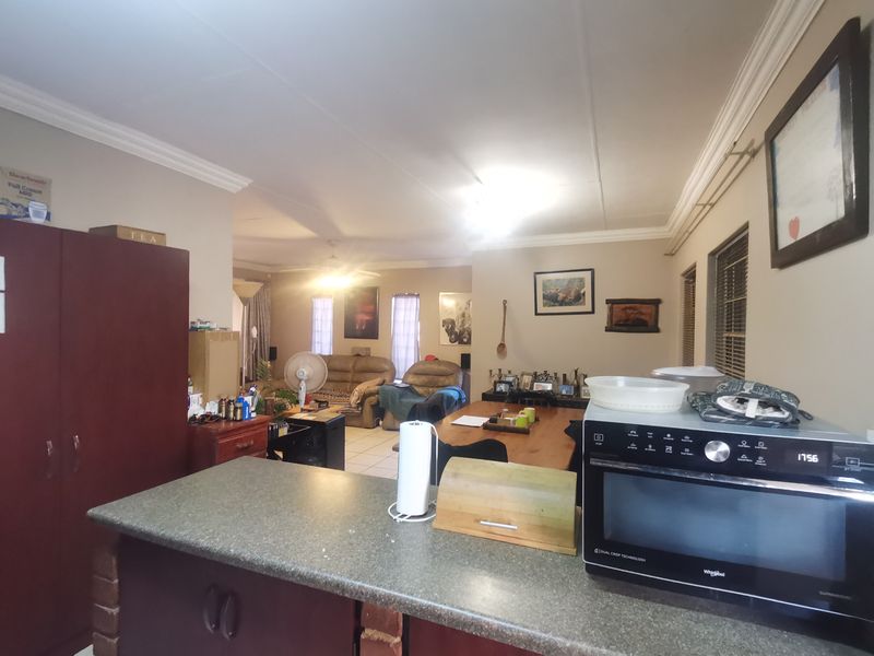 Open plan living and kitchen area featuring tiled flooring, neutral wall tones, and built-in cabinetry with a breakfast counter.