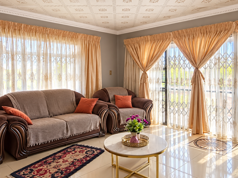 Spacious living room featuring tiled flooring, decorative ceiling detail, and large sliding glass doors with security gates leading to the exterior.