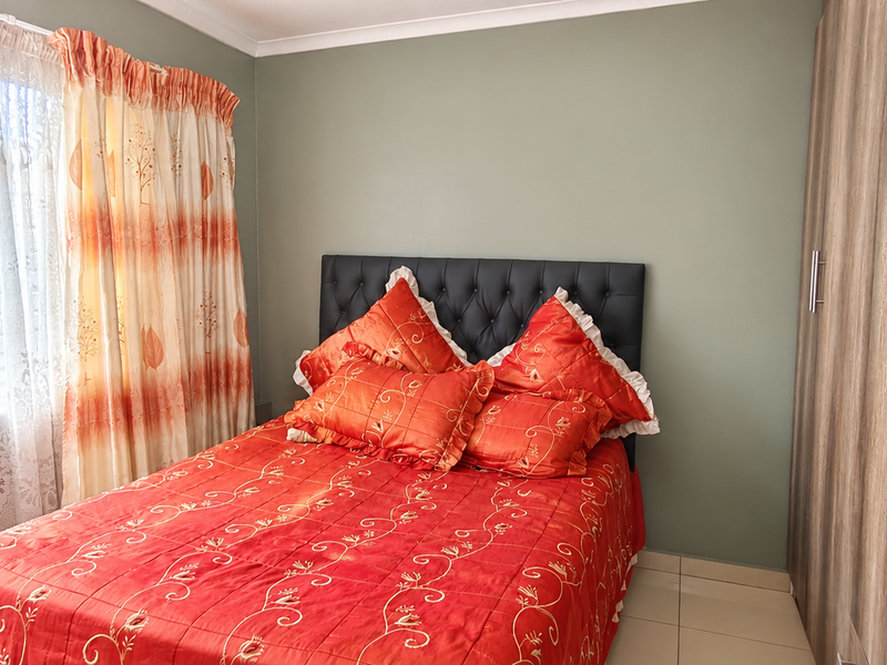 A well-maintained bedroom featuring neutral wall tones, tiled flooring, and extensive built-in wooden cupboards providing ample storage space.