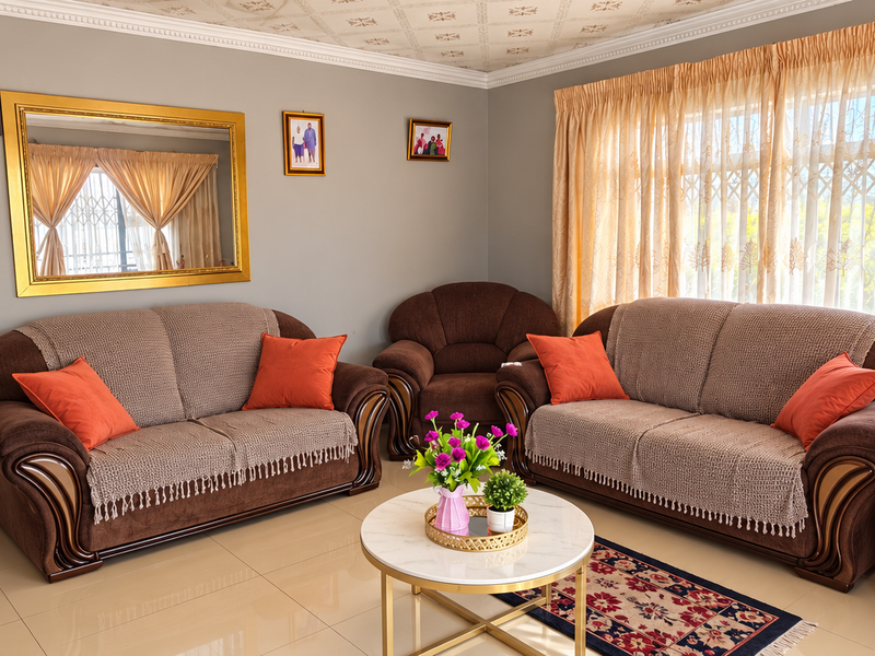 A well-maintained living room featuring tiled flooring, decorative ceiling detailing, and a large window with natural light.