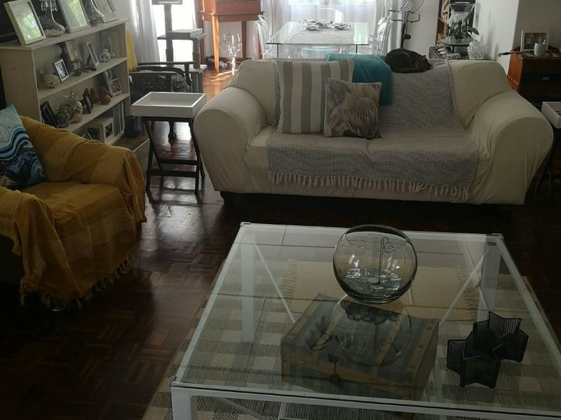 A spacious living room featuring classic parquet flooring, neutral walls, and large windows that provide ample natural light.
