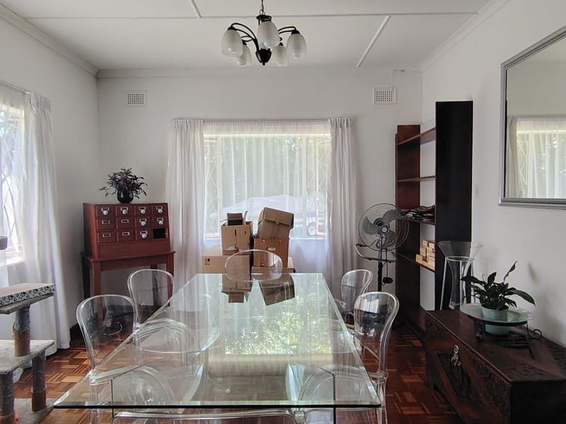 A dining room featuring classic parquet flooring, large windows with natural light, and a built-in shelving unit.