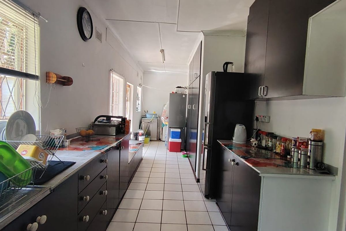A functional galley-style kitchen featuring dark cabinetry, tiled flooring, and ample counter space, offering a practical layout for daily meal preparation.