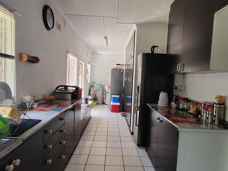 A functional galley-style kitchen featuring dark cabinetry, tiled flooring, and ample counter space, offering a practical layout for daily meal preparation.