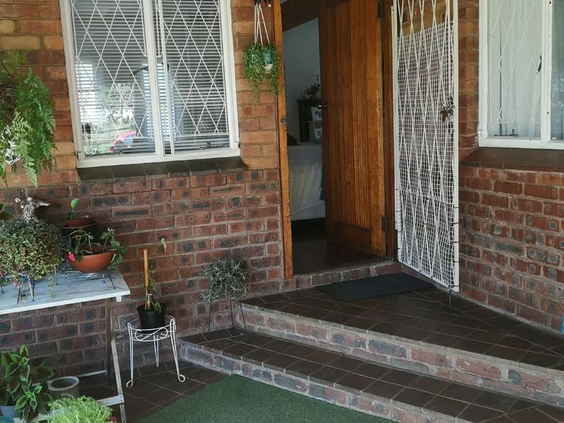 Front entrance featuring a covered porch with face brick walls, tiled steps, and a secure timber door with security gate.
