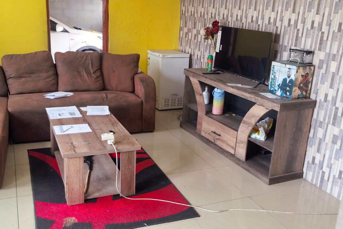 A living room featuring tiled flooring and decorative ceiling cornicing, currently requiring cosmetic updates to the wall finishes.