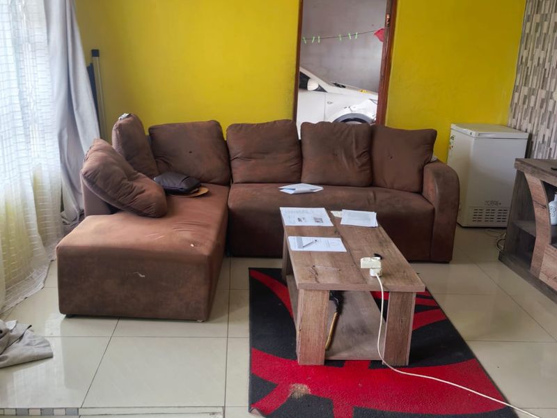 A living room featuring tiled flooring and decorative ceiling cornicing, currently requiring cosmetic updates to the wall finishes and flooring.