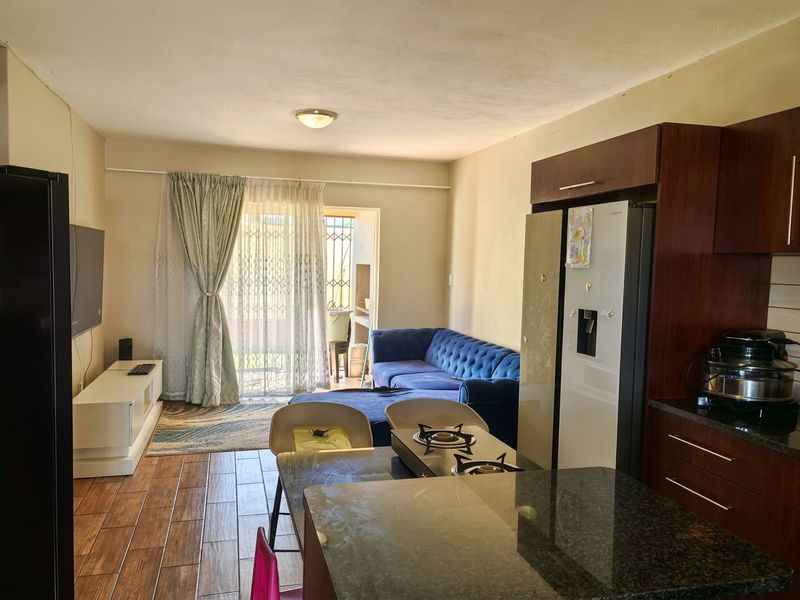 Open-plan living area featuring a kitchen with granite countertops and gas hob, flowing into a lounge space with access to an outdoor patio.