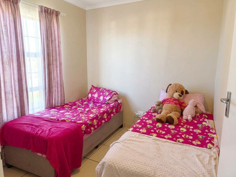 A functional bedroom featuring tiled flooring and natural light through a window with curtain rails.