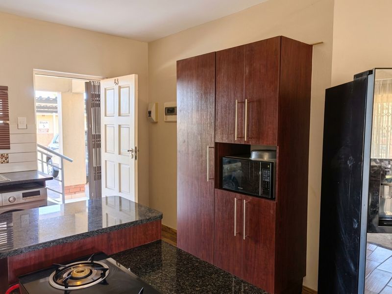 Kitchen featuring dark wood cabinetry, granite countertops, a built-in gas hob, and integrated microwave, with direct access to the exterior.