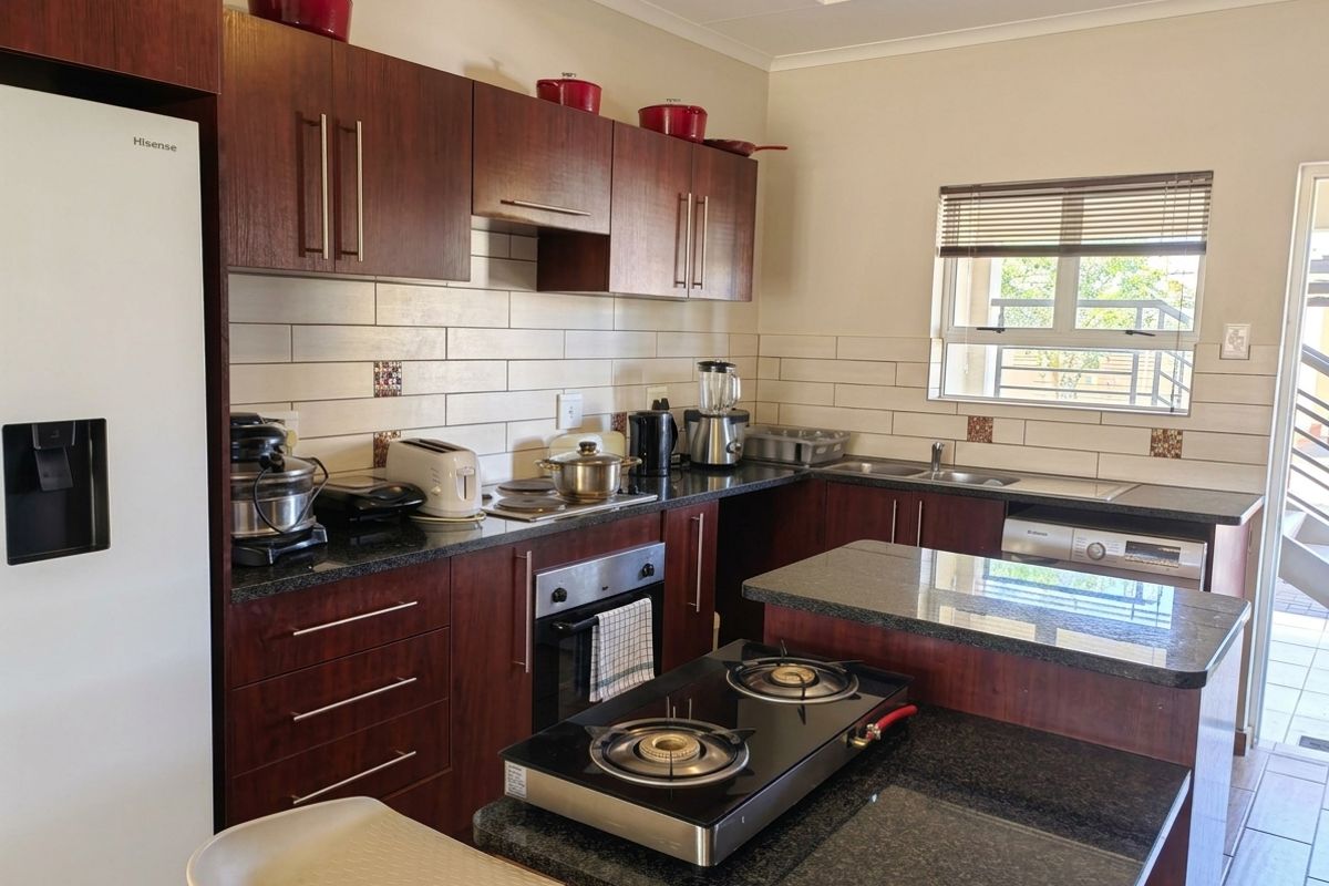 A functional kitchen featuring dark wood cabinetry, granite countertops, a built-in oven, gas hob, and a subway tile backsplash with natural light.