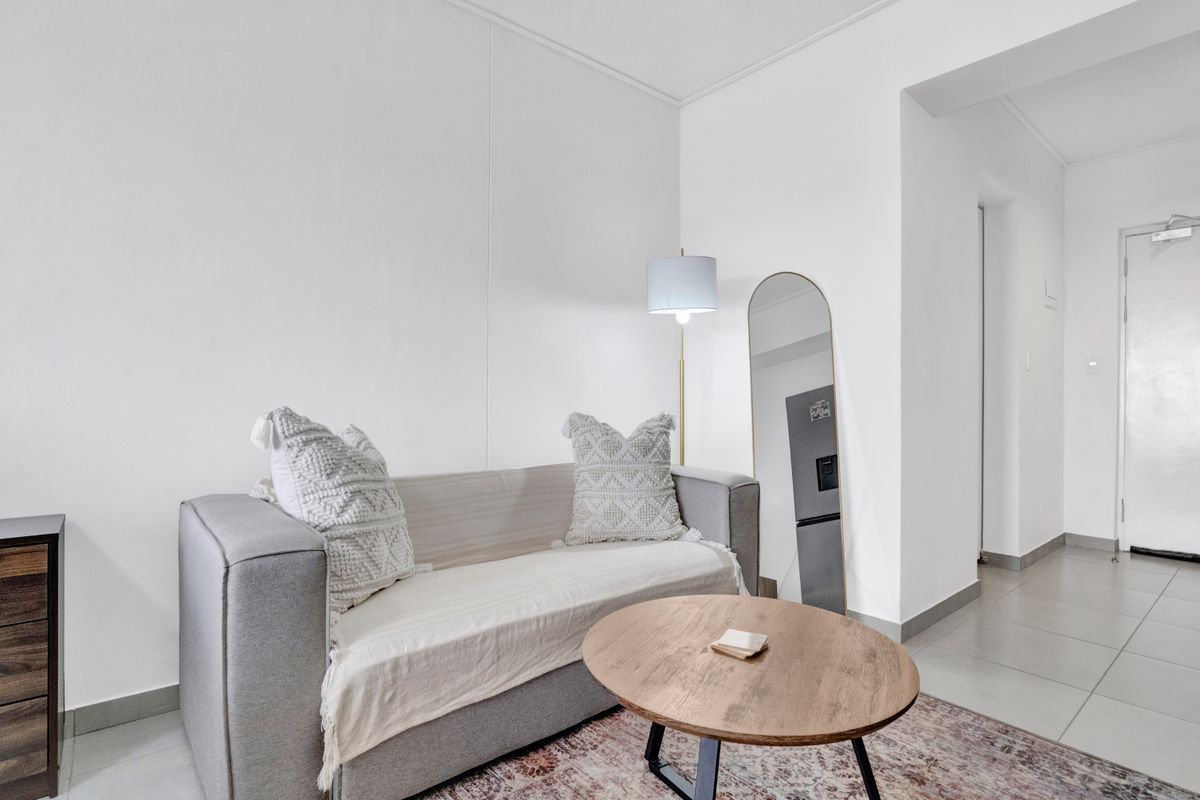 A bright and neutral living area featuring clean white walls and modern tiled flooring, providing a versatile space for relaxation.
