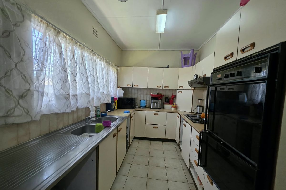 A functional kitchen featuring built-in cabinetry, a stainless steel sink, integrated oven, and cooktop, offering a dated layout ready for modernization.
