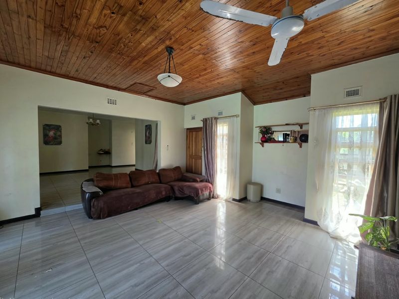 Spacious living area featuring high timber tongue and groove ceilings, tiled flooring, and a ceiling fan, offering a warm and functional living space.