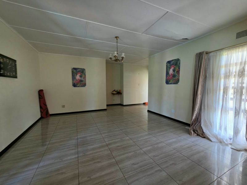 Spacious living area featuring tiled flooring and a sliding glass door, requiring ceiling repairs to restore the space.