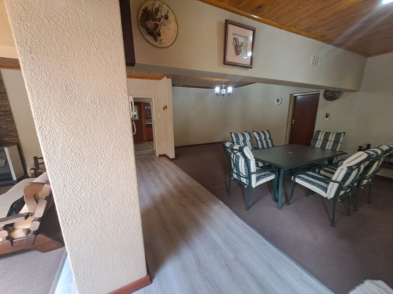 Open plan living and dining area featuring a combination of laminate and carpet flooring with a timber ceiling and built-in fireplace.