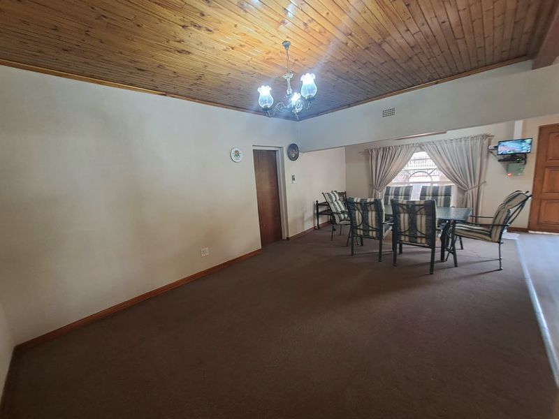 Spacious dining area featuring a traditional timber tongue and groove ceiling, chandelier lighting, and carpeted flooring, offering a classic foundation for updates.