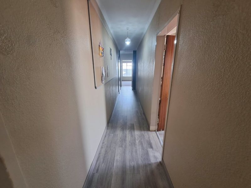 A functional hallway featuring modern laminate flooring and neutral wall finishes, providing access to adjacent rooms within the home.